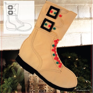 May include: A tan felt boot stocking with black buckles, red and green pom-poms, and a black outline. The stocking is hanging from a fireplace.