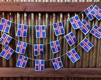 May include: A string of Icelandic flags hanging on a rusty metal fence. The flags are blue, white, and red with a red cross in the center.