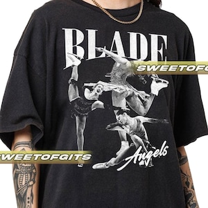 Puede incluir: Camiseta gris oscuro con la palabra "BLADE" en letras blancas grandes sobre un gráfico en blanco y negro de patinadores sobre hielo. La palabra "Angels" está escrita en cursiva debajo.