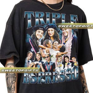 Könnte beinhalten: Schwarzes T-Shirt mit einem Grafikdesign, das mehrere lächelnde Frauen und die Worte "TRIPLE ESPRESSO" in blauer und weißer Schrift zeigt. Das T-Shirt hat einen Vintage-Look.