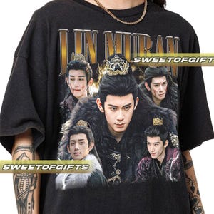 May include: Dark gray t-shirt featuring a graphic of several Asian men in ornate costumes and crowns. The text "LIN MURAN" is printed across the top in gold lettering. The shirt has the text "SWEETOFGIFT" printed on it.