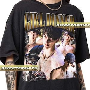 以下が含まれることがあります： 「GIRL DINNER」の文字と男性のコラージュが描かれた、金と白のグラフィックが特徴の黒いTシャツ。クルーネックと半袖のデザインです。「SWEETOFGIFT」の文字がプリントされています。