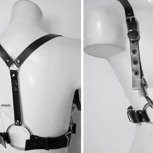 May include: Black leather harness with silver hardware and a large ring in the back. The harness has adjustable straps and a buckle closure.