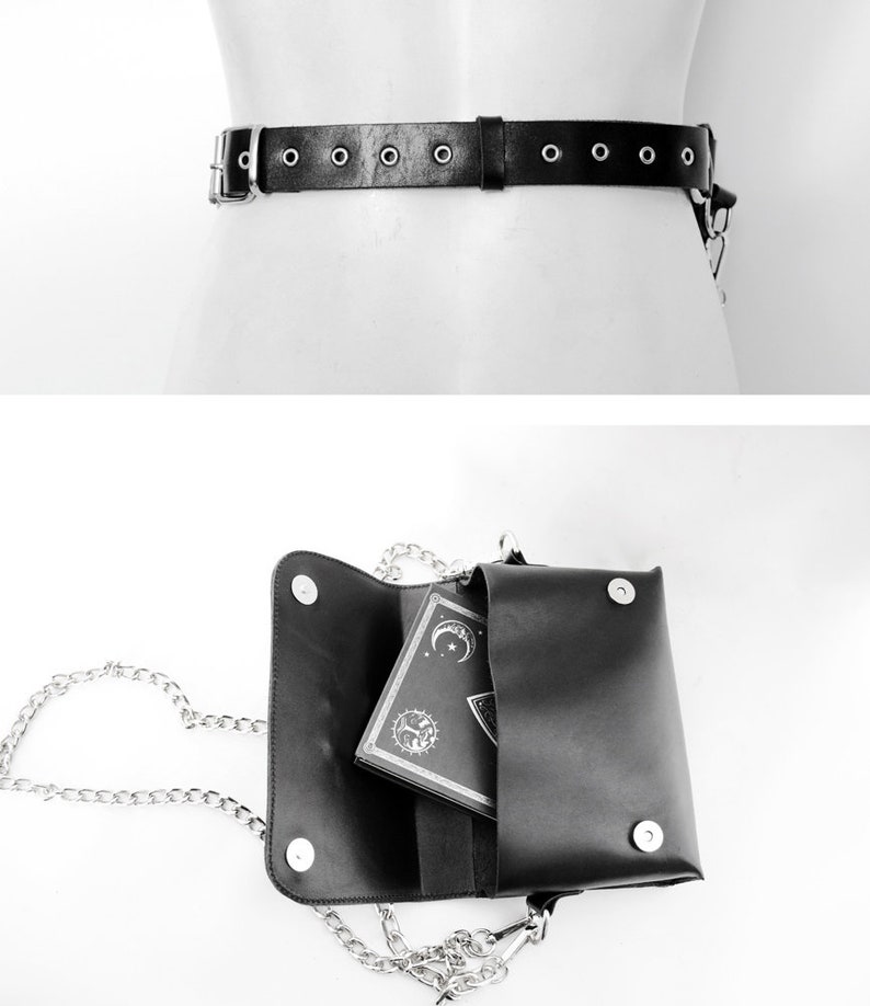 May include: A black leather belt with silver metal accents and a matching black leather bag with a silver chain strap. The bag is open and a small black book with a silver design is inside.