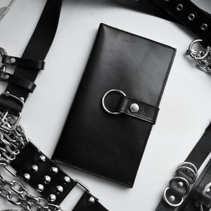CARTERA CON ARNÉS DE ANILLA TÓRICA: Cartera de cuero genuino con cierre a presión y detalle de junta tórica