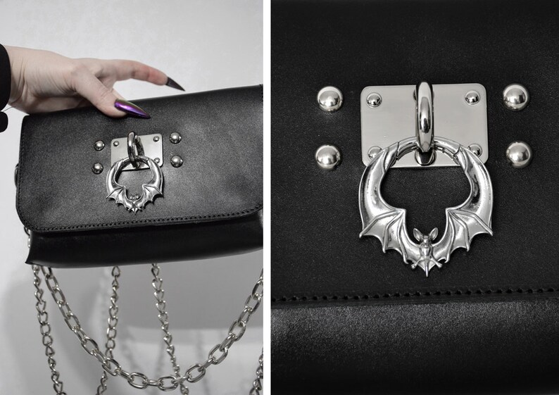 May include: Black leather crossbody bag with a silver bat-shaped clasp and a silver chain strap.