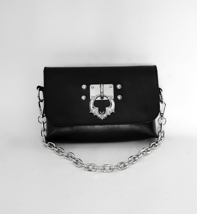 May include: Black leather shoulder bag with a silver bat-shaped clasp and a silver chain strap.