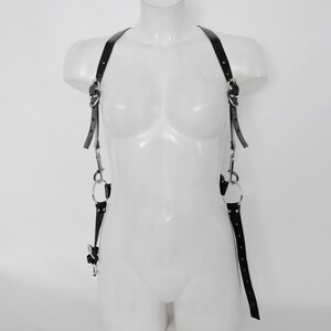 May include: Black leather harness with silver hardware and adjustable straps. The harness has two D-rings on each side and two O-rings on each side.