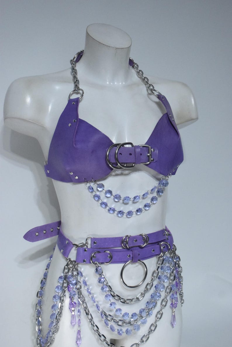 May include: A purple leather-like halter top and matching belt set featuring silver-tone metal chains, O-rings, and buckles. The garment is adorned with multiple strands of dangling light purple faceted crystal beads and silver metal chains.