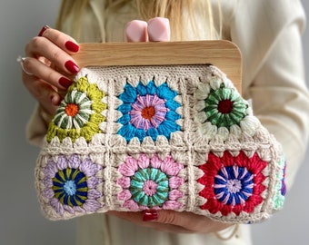 May include: A crocheted handbag with a wooden frame and colorful floral designs. The bag is made of beige yarn with squares of different colors, including green, blue, pink, and red.