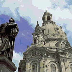 May include: A statue of a man in a long robe stands in front of a large, ornate church with a dome. The church has a tall spire and many windows.