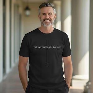 Peut inclure: T-shirt noir avec l'inscription blanche "THE WAY THE TRUTH THE LIFE" et une ligne verticale. Le texte "JOHN 14:6" est en dessous de la ligne. Le t-shirt est porté par une personne.