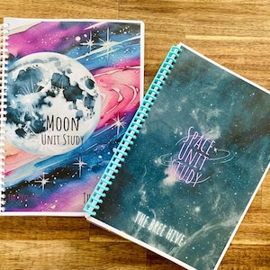 Puede incluir: Dos cuadernos de espiral con tapas de temática espacial. El primer cuaderno tiene una ilustración de acuarela de la luna y las estrellas con el texto "Moon Unit Study". El segundo cuaderno tiene una ilustración de acuarela de una galaxia con el texto "Space Unit Study" y "The Bree Hive".
