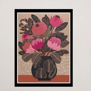May include: A framed art print featuring a floral arrangement in a black vase. The bouquet includes pink and red protea flowers, dark green leaves, and brown accents. The background is tan with a patterned design, and the frame is black.