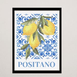 Peut inclure: Impression encadrée avec une illustration à l'aquarelle de citrons sur une branche avec des feuilles vertes. Le fond présente un motif de carreaux bleus et blancs. Le mot "POSITANO" est imprimé en bas en bleu.