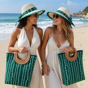 May include: Two women on a beach, each holding a green tote bag with a woven handle. They wear wide-brimmed straw hats with green patterned bands and matching bows. The bags have a green and white dotted pattern.