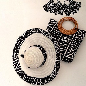 May include: A black and white patterned sun hat, a matching tote bag with a woven handle, and a pair of earrings with the same pattern.