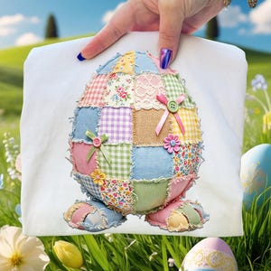 Può includere: Decorazione a forma di uovo di Pasqua in tessuto bianco con un design patchwork. L'uovo è realizzato con quadrati di tessuto di vari colori pastello, con motivi floreali e a quadri. Ha bottoni e fiocchi rosa e verdi.