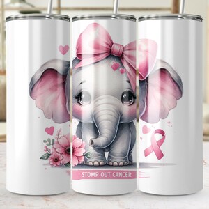 May include: A white tumbler with a pink ribbon, pink flowers, and a pink bow on a gray elephant. The text "STOMP OUT CANCER" is printed on the tumbler.