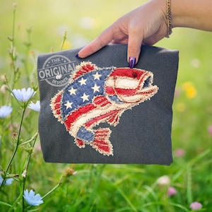 Może przedstawiać: Biały ceramiczny kubek z czarnym uchwytem i napisem "But First, Coffee" pogrubioną, czarną czcionką. Kubek jest umieszczony na rozmytym tle, sugerującym przytulne otoczenie.