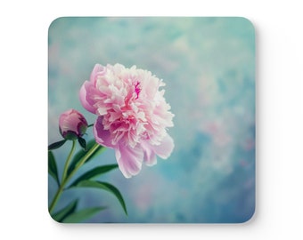 May include: A single pink peony flower with a bud on a stem against a blue and white background.