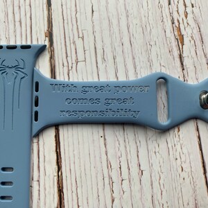 May include: A light blue silicone watch band with a Spiderman logo and the quote "With great power comes great responsibility" engraved on it.