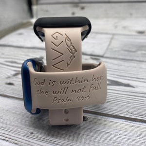 Puede incluir: Correa de reloj Apple Watch beige claro con el texto "Dios está en ella, no caerá. Salmo 46:5" y un gráfico de montaña. El reloj tiene una esfera negra y un acento azul.