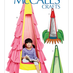 May include: A sewing pattern for a hanging chair for kids. The pattern includes three different designs: a pink and yellow chair with ruffles, a green chair with a window, and a red and green chair with a window and a star design. The pattern is from McCall's Crafts and the pattern number is M7614.