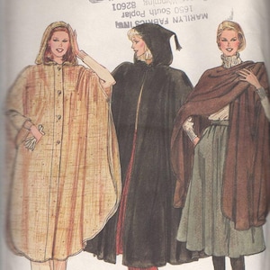 May include: Vogue sewing pattern featuring three hooded capes. The capes are in tan, black, and brown. The pattern is labeled "Very Easy Vogue" and includes the size "ONE SIZE". The image is a vintage illustration.