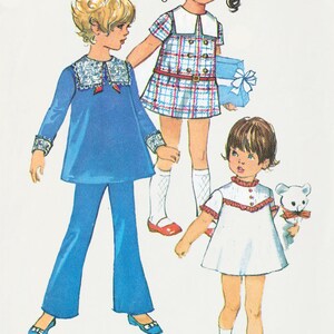 May include: Three girls wearing different dresses. The girl on the left is wearing a blue dress with a white collar and white pants. The girl in the middle is wearing a plaid dress with a white collar and a white belt. The girl on the right is wearing a white dress with a red collar and a red bow. The girl in the middle is holding a blue box with a white bow.