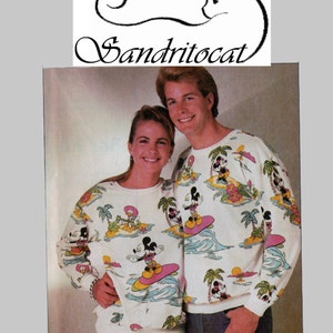May include: White sweatshirts with a tropical Mickey Mouse print. The sweatshirts feature Mickey Mouse surfing, palm trees, and waves. The image also includes the text "OVERLOCK/SERGER" and "Sandritocat".