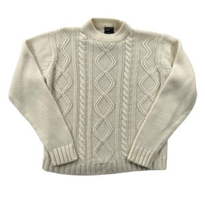 May include: An off-white long-sleeve sweater featuring a mock neck collar and a textured cable knit pattern with vertical braided columns and diamond shapes across the front. The garment has ribbed cuffs and a ribbed hem at the bottom edge.