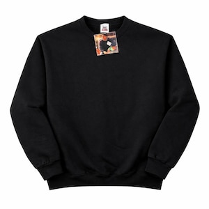 May include: A black crew neck sweatshirt with a small tag attached near the collar. The tag features a color image of a person. The sweatshirt has long sleeves and a ribbed hem and cuffs. The fabric appears to be a soft, comfortable material.