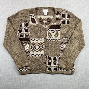 May include: A brown cardigan sweater with a V-neck and button closure. The sweater features a patchwork design with various patterns in shades of brown, cream, and white. The sleeves are long, and the overall style is vintage.
