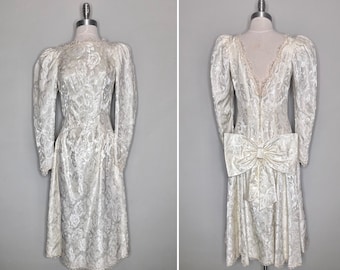 Victoriaanse Revival-trouwjurk jaren 80: crème satijnbrokaat, oversized strik (maat 7/8)