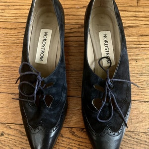 Puede incluir: Un par de zapatos negros de cuero y ante con cordones y recortes. Los zapatos tienen punta puntiaguda y tac&oacute;n bajo. El nombre de la marca "Nordstrom" es visible en el interior de cada zapato.