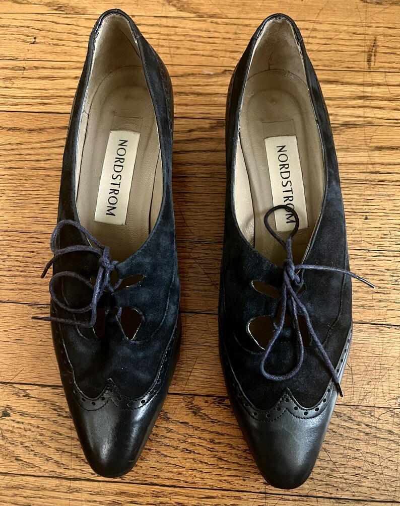 Puede incluir: Un par de zapatos negros de cuero y ante con cordones y recortes. Los zapatos tienen punta puntiaguda y tac&oacute;n bajo. El nombre de la marca "Nordstrom" es visible en el interior de cada zapato.