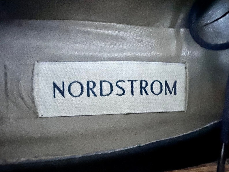 Puede incluir: Una etiqueta blanca con la palabra "Nordstrom" impresa en letras negras.