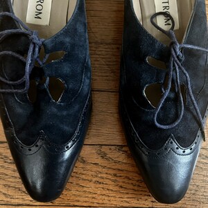 Puede incluir: Un par de zapatos de ante azul marino con cierre de cordones y un dise&ntilde;o decorativo de corte. Los zapatos tienen una punta puntiaguda y una suela de cuero. El nombre de la marca "TROM" es visible en el interior de los zapatos.