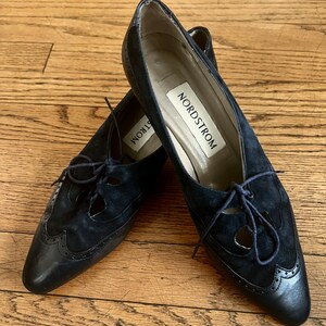 Puede incluir: Un par de zapatos negros de ante con cordones, recortes y punta puntiaguda. Los zapatos tienen suela de cuero y una etiqueta de Nordstrom en el interior.
