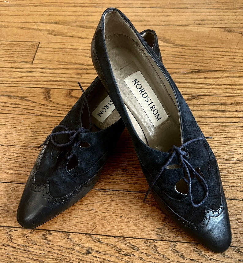 Puede incluir: Un par de zapatos negros de ante con cordones, recortes y punta puntiaguda. Los zapatos tienen suela de cuero y una etiqueta de Nordstrom en el interior.