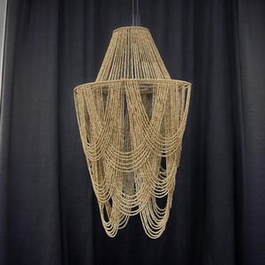 May include: A large, beaded chandelier with a cascading design. The chandelier is made of natural materials and has a warm, earthy tone.