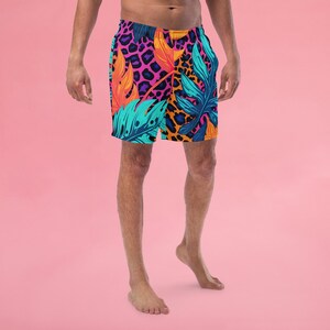 Peut inclure: Un short de bain coloré avec un imprimé tropical composé de feuilles roses, orange, bleues et vertes et un motif léopard.