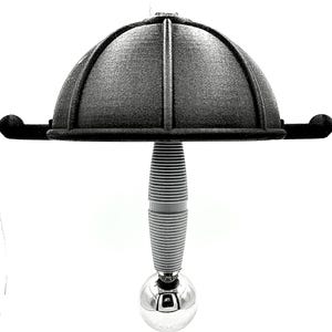 May include: A black, dome-shaped bottle stopper with a textured surface. The stopper has a ribbed gray stem and a shiny silver ball at the bottom. The design resembles a hat.