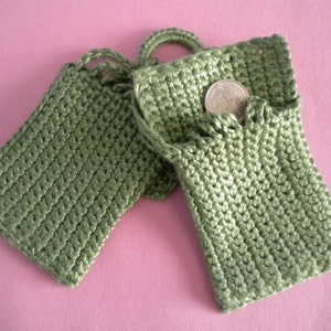 Pode incluir: Duas pequenas bolsas de crochê verde com uma moeda dentro de uma das bolsas.