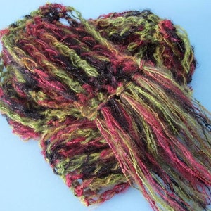 May include: A crocheted scarf with long fringe in shades of red, green, and black.