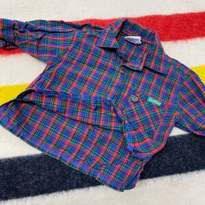 Puede incluir: Una camisa de manga larga a cuadros rojos, azules y verdes con cuello abotonado y un peque&ntilde;o parche verde con el texto "Oak Creek" en el pecho izquierdo.