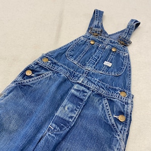 May include: Blue denim overalls with brass-colored buttons and adjustable straps. Features multiple pockets and the Lee brand label. The overalls are a classic style, suitable for various activities.