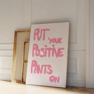 May include: A white canvas print with pink lettering that reads "Put your positive pants on".