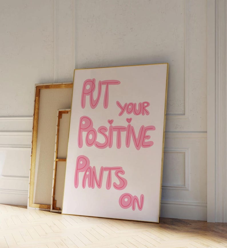 May include: A white canvas print with pink lettering that reads "Put your positive pants on".